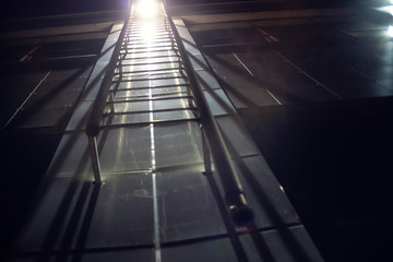 Fire metal ladder on lit at night, photo from bottom to top