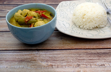 Green curry with fish balls and steamed rice on a wooden table