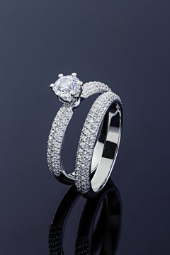 Female engagement and wedding rings with diamonds on black background