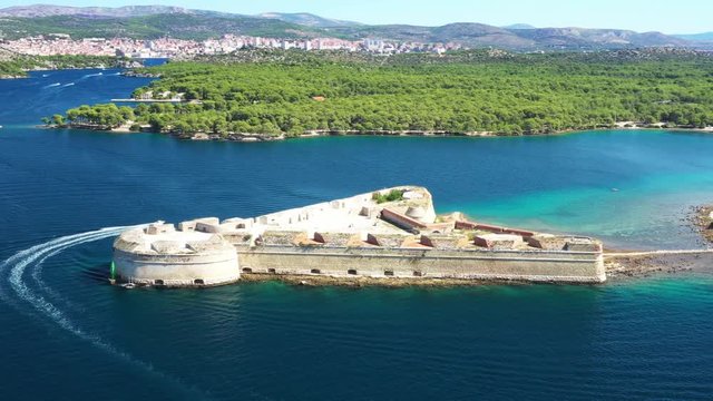 St. Nicholas fortress at Sibenik bay entrance and boat passing by, archipelago od Dalmatia, Croatia, drone circle footage