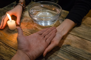 Divination with a candle on the water. hand of a fortune teller and the hand of a man. concept of magic, divination