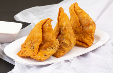Indian Street Food Samosa or Samosas is a Crispy And Spicy Triangle Shape Snack Which Has Crisp Outer Layer of Maida & Filling of Mashed Potato, Peas And Spices. Served With Chutney, Ketchup or Curd