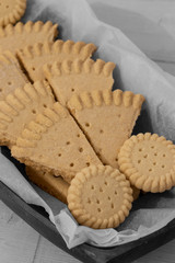 Shortbread biscuits cookies on greaseproof paper in a wooden bowl. Selective colour