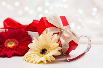 Red gift boxes with ribbons, heart and flowers on a white delicate background with bokeh.
