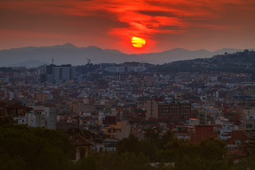 view of the city of Barcelona, capital of province of Catalonia Spain at sunset in summer in front of mountains with red salt and residential buildings in shade