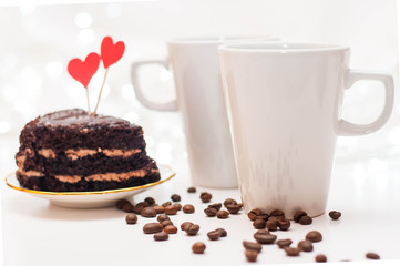 red gift boxes with ribbons, a pair of white cups and flowers on a white delicate background with bokeh.