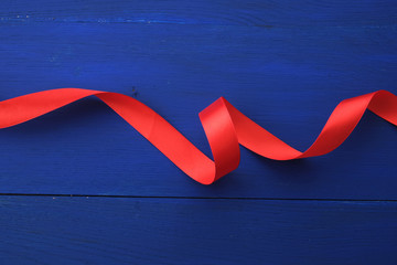 red silk thin ribbon twisted on a blue wooden background