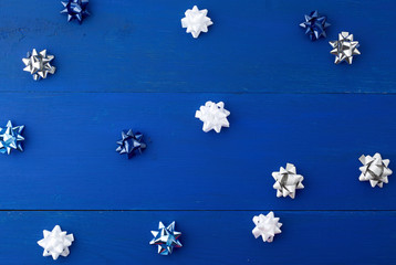 white, blue and gray bows for gifts on a blue wooden background