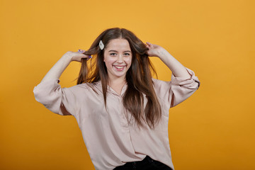 Happy caucasian woman in fashion pastel shirt fluttering hair, smiling isolated on orange background in studio. People sincere emotions, lifestyle concept.
