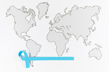 World Cancer Day with ribbon symbol on blur gray world map background. Selective focus. Soft ficus. Top view. Medicine concept.