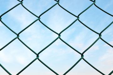 Chainlink wire fence against a morning blue sky for prison and security concept