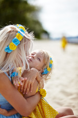Happy family relaxing by the sea. Happy family resting at beach in summer.Young mother and her adorable little daughters on beach vacation. Concept of summer,childhood and leisure