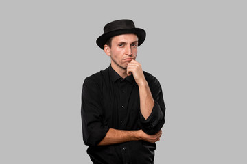 Stylish handsome man a black shirt and pork pie hat isolated over grey background.