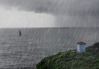 Rainy day by the ocean. Dark cloud in the sky. Sailboat in the water. Green grass on the shore. - 314430616