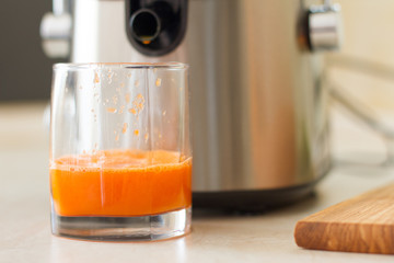 the process of making juice in the kitchen. A glass of fresh carrot juice. carrot and Apple on the table. detoxification, vegetarian diet. juicy healthy vitamin drink. refreshing fruit drink. juicer.