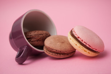 Closeup of french macarons falling from cup of coffee on pink background
