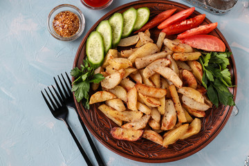 Baked potatoes served with tomatoes, cucumbers and parsley on a plate, Top view, Horizontal orientation