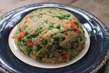 Fried rice with vegetables on blue plate close up view. Asian cuisine concept