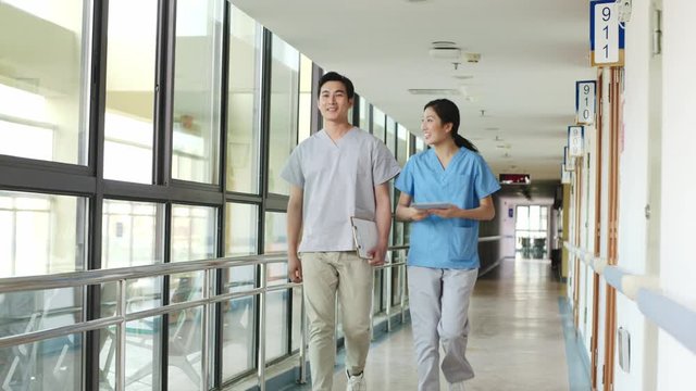 two young asian healthcare professional walking in hallway of hospital or nursing home