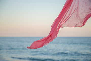 Pink scarf in the air on the beach.