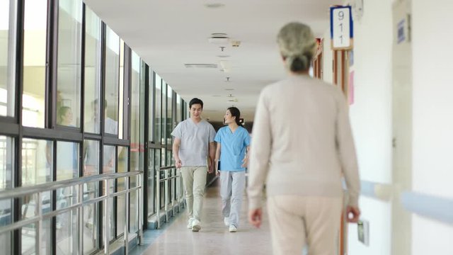 two young asian healthcare professional walking talking and greeting senior people in hallway