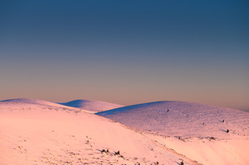 Fototapeta na wymiar White hills covered by snow under blue sky, edit space
