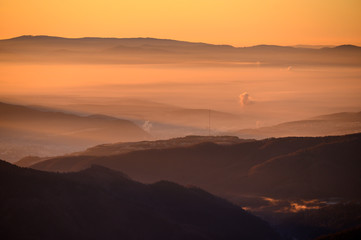 Sunrise in mountains, shape of hills in morning mist, white edit space