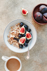 Top view of a breakfast bowl with granola, blue grape and fig slices. Healthy vegan eating flat lay
