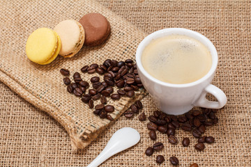 Cup of coffee, macaroons and coffee beans on sackcloth