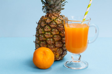 Fresh tropical fruits and glass of juice on blue background.
