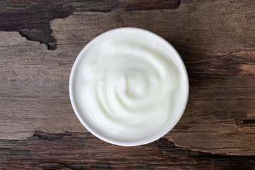 Yogurt greek white clean In bowl with spoon on a wooden background from top view.