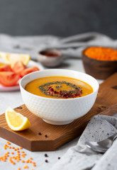 A bowl of thick red lentil soup served with lemon, dried mint and paprika. Turkish and Indian cuisine. Vertical orientation
