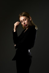 blonde in a black suit on a black background. Business woman