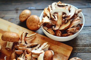 Royal fresh mushrooms on a wooden background. Sliced ​​champignons on a wooden board. Cooking process.