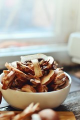 Royal fresh mushrooms on a wooden background. Sliced ​​champignons in a white bowl. Cooking process. Vertical view 
