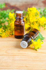 Two small bottles with essential St John's-wort oil (extract, tincture, infusion) on the old wooden background. Aromatherapy, spa and herbal medicine ingredients.