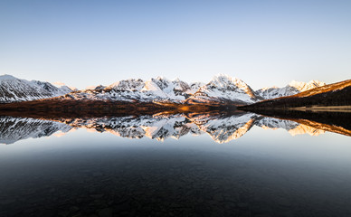 Beautiful reflection of snow covered mountains at a lake in northern norway at sunrise