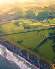 Farm and pastures near cliffs and ocean at golden hour