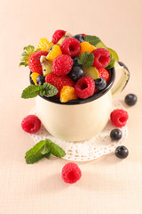 fruit salad with berries fruits, orange and kiwi in mug