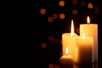 burning candles glowing in dark with bokeh lights on background