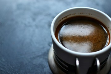 Natural coffee in a white cup. Coffee top view. Coffee with cream on a dark, dark blue background. Place for text.