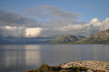 View to the sea and Vega archipelago mountains from the foot of the mountain Torghatten in Torget island in Brønnøy Municipality in Nordland county, Norway on sunny summer evening