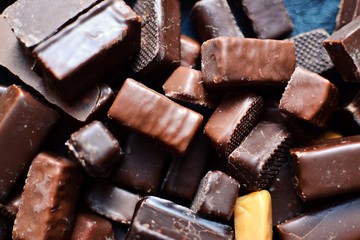 Assortment of chocolates. Candies on a dark bluish background. Top view place for text. Dark chocolate. Chocolate bars.