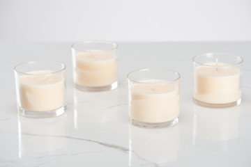 white candles in glass on marble white surface