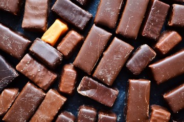 Assortment of chocolates. Candies on a dark bluish background. Top view place for text. Dark chocolate. Chocolate bars.