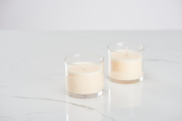 white candles in glass on marble white surface