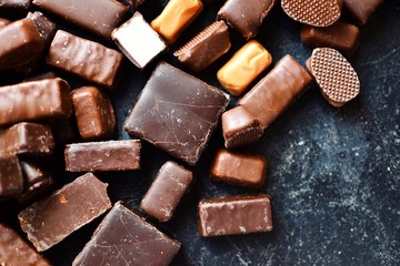 Assortment of chocolates. Candies on a dark bluish background. Top view place for text. Dark chocolate. Chocolate bars.
