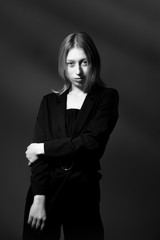Blonde with long hair in a black suit on black background, black and white. Business woman