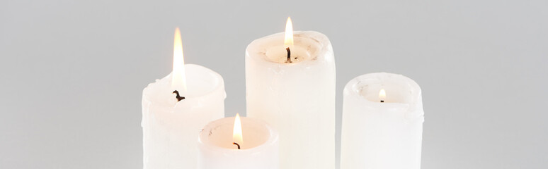 white burning candles glowing isolated on grey, panoramic shot