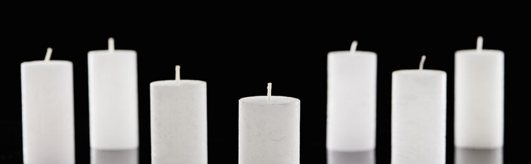 Naklejka premium selective focus of white candles isolated on black, panoramic shot